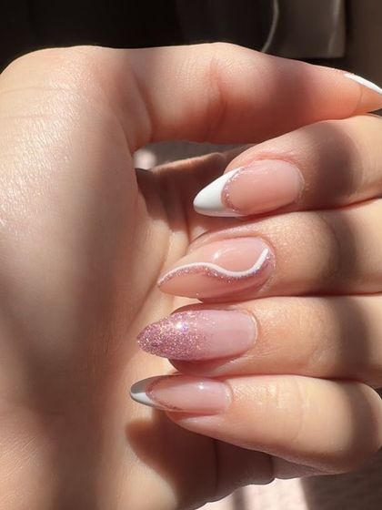 A sunny day calls for pretty nails. This set features a classic white French tip, a pink glitter ombre nail, and a delicate white swirl accent.