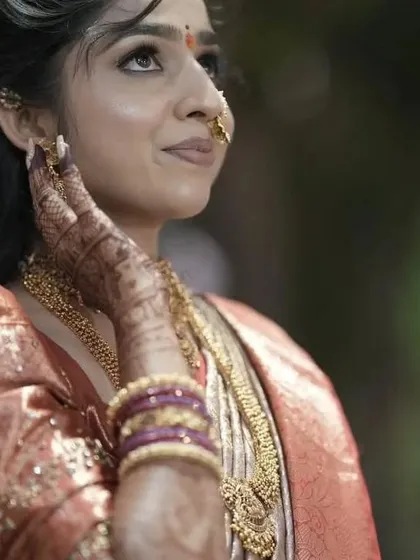 A candid shot of a beautiful bride on her engagement day, her mehendi-adorned hand gently touching her face.