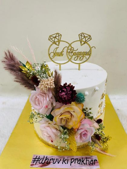 A rustic and romantic "Just Engaged" cake. This design is beautifully decorated with a variety of dried and fresh flowers, creating a bohemian-chic vibe.
