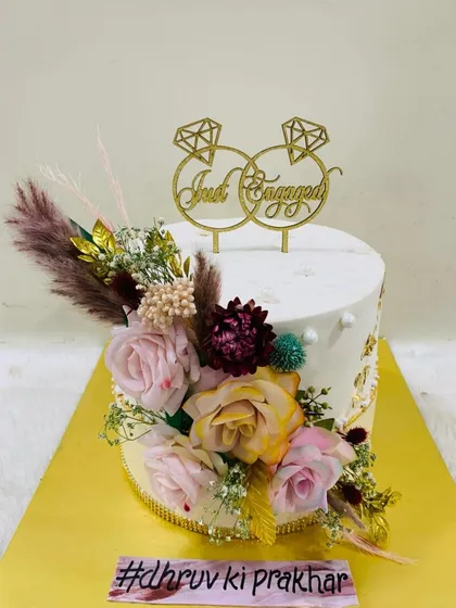A rustic and romantic "Just Engaged" cake. This design is beautifully decorated with a variety of dried and fresh flowers, creating a bohemian-chic vibe.