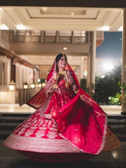 A bride's joyful twirl at her wedding venue. The motion of her red lehenga creates a dynamic and celebratory photograph.