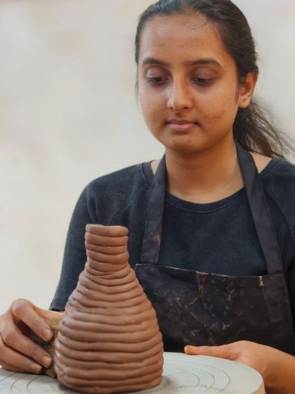 This student is building a vase using the coiling method. By stacking and blending clay coils, she can create tall, curved forms that would be difficult to make otherwise.