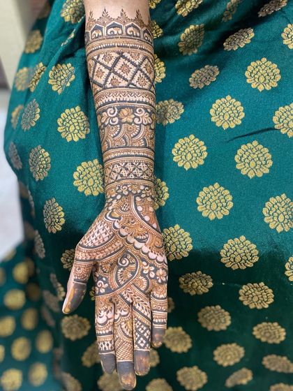 A single arm view of a detailed bridal design, showing the combination of different bands of patterns, including jaali, leaves, and florals.