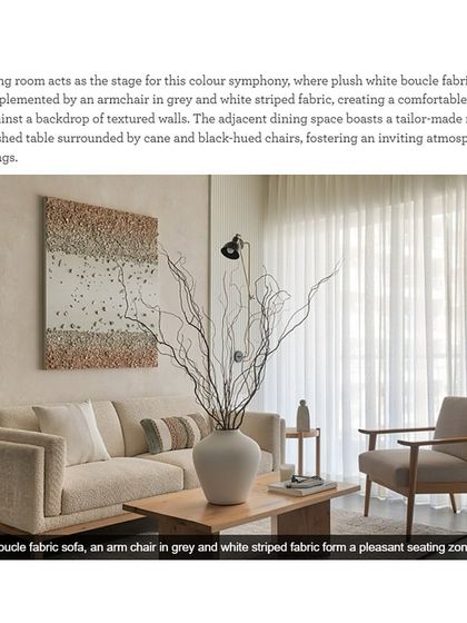 This image from our feature shows the living room acting as a stage for a color symphony. Plush white boucle fabrics are complemented by an armchair in grey and white striped fabric, creating a comfortable seating area.