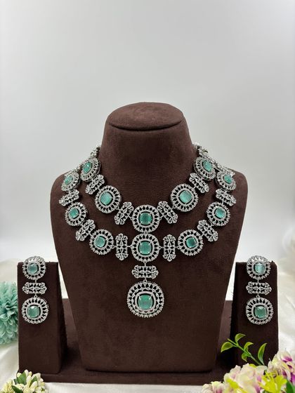 This bold, silver-plated AD set features large circular motifs. It's a statement piece available in sapphire blue, emerald green, ruby red, and all-white, perfect for customers who want to stand out.