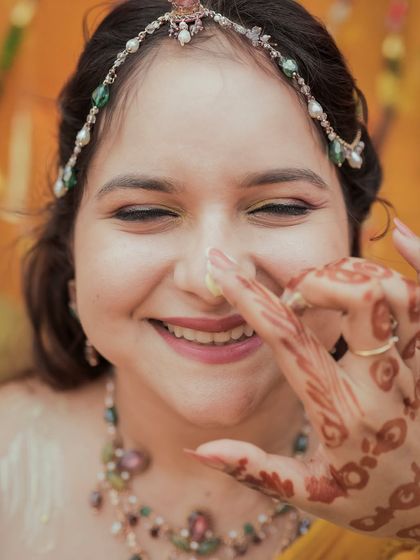 A playful moment where the groom dabs haldi on the bride's nose, capturing her smiling reaction.