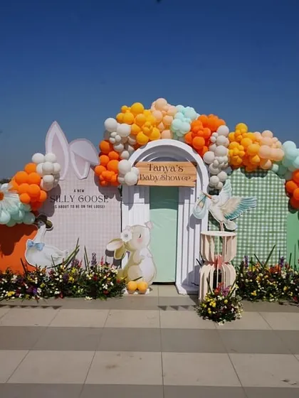 For this rooftop bunny-themed baby shower, I created a vibrant and cheerful backdrop against the open sky. The setup features a white picket fence, lush florals, and a playful balloon arch in pastel and orange tones, perfect for a sunny day.