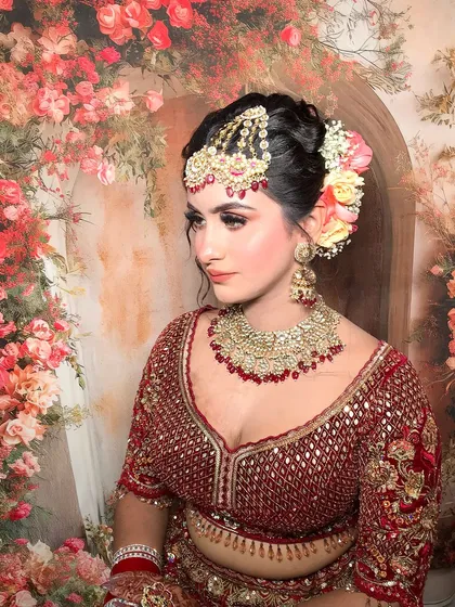 This bride is a vision in red and gold, with coral-toned makeup. Her look is completed with a heavy kundan and ruby choker and a mathapatti.
