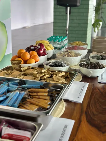 A closer look at the nutritious food we provide. The spread includes fresh fruits like oranges and apples, assorted nuts, and healthy multi-grain bars to nourish the body.