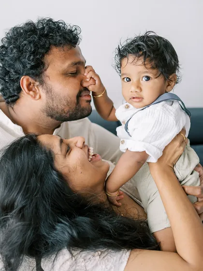 A playful moment between a mother, father, and their son. The baby reaching for his dad's nose is a perfect, candid memory.