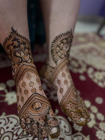 An elegant and asymmetrical design for the feet, with a large peacock motif on one side and flowing patterns on the other.