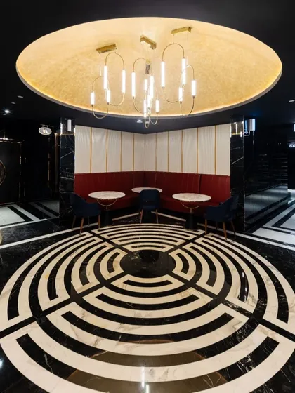 A striking feature in the INOX Jalosa lobby is this circular seating area, defined by a dramatic labyrinth-style floor inlay. The design creates a natural gathering point and a strong visual anchor in the space, complemented by a modern chandelier that casts a warm glow.