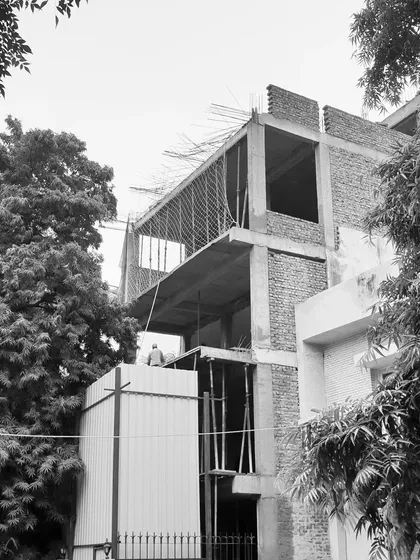 The building's structure mid-construction, showing the combination of a concrete frame and brick infill walls. The open sections are designed for large windows to maximize natural light.