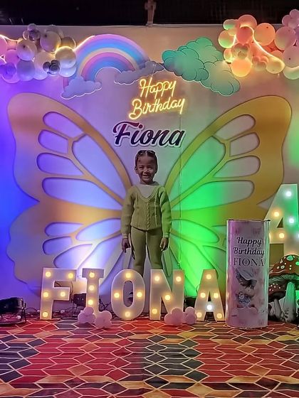 A whimsical butterfly theme for a 4th birthday. The birthday girl becomes part of the decor with giant butterfly wings on the backdrop, surrounded by pastel balloons, princess cutouts, and her name in marquee letters.
