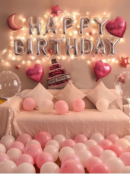 A classic pink and white balloon setup with "Happy Birthday" foil letters and fairy lights.