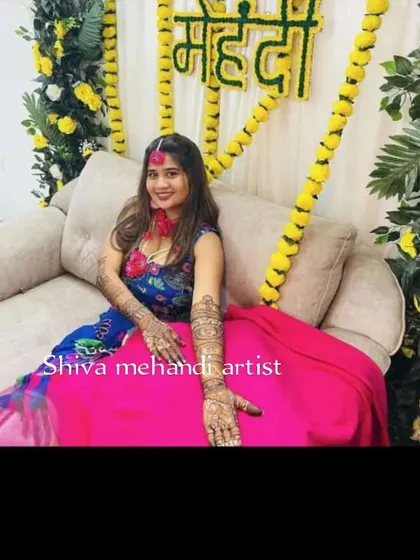 A beautiful bride at her mehendi ceremony, showing off the intricate henna art that extends up her forearms.