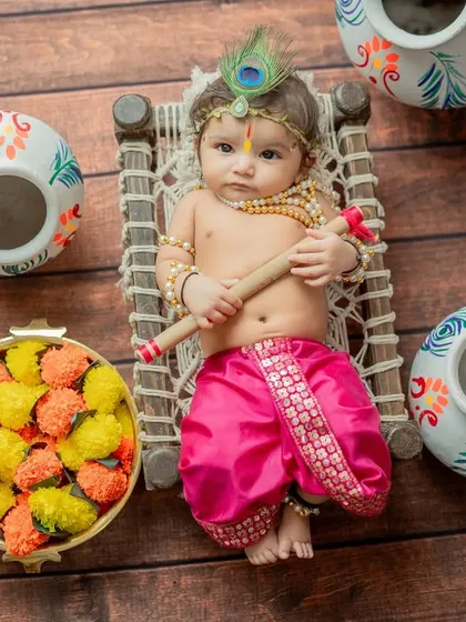 An overhead view of the baby Krishna on the cot, surrounded by decorated pots.