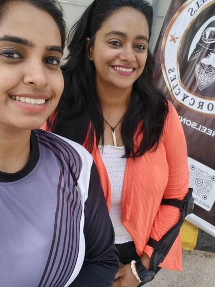 Two graduates take a selfie in front of the Heels on Wheels banner. They are proud members of our community.