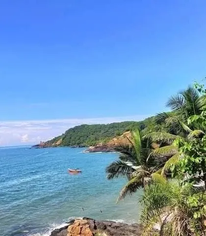 A view of the beautiful coastline from a viewpoint in Gokarna, with clear blue water and lush greenery.