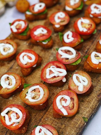 My Cheese Corn Nuggets presented as canapés. Each nugget is topped with a slice of fresh tomato and a swirl of mayonnaise, making them visually appealing and delicious.
