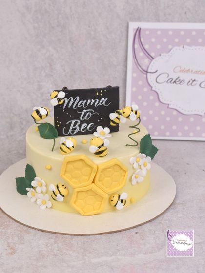 A "Mama to Bee" themed cake for a baby shower, decorated with cute fondant bees and honeycomb.