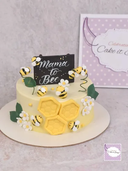 A "Mama to Bee" themed cake for a baby shower, decorated with cute fondant bees and honeycomb.