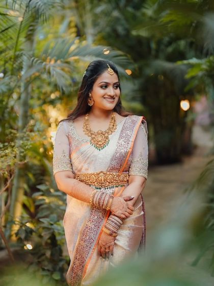 A bride walks through a garden, her pastel saree looking fresh and elegant against the lush greenery.