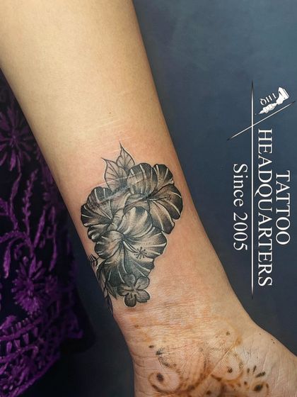 A bouquet of hibiscus flowers tattooed on the wrist, a beautiful floral piece with detailed shading.