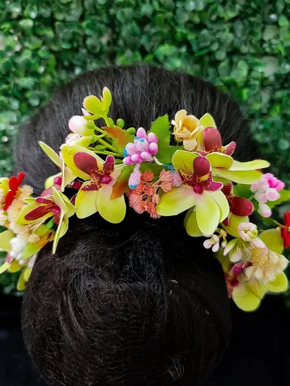 A unique hair veni with light green orchids and other colorful flowers, ideal for a tropical or garden-themed wedding.
