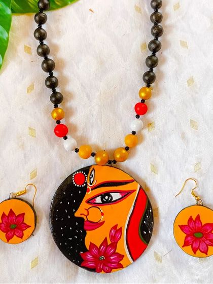 This hand-painted goddess pendant combines a serene facial expression with vibrant lotus flowers. The dark, starry background adds a touch of mystery and elegance to the design.