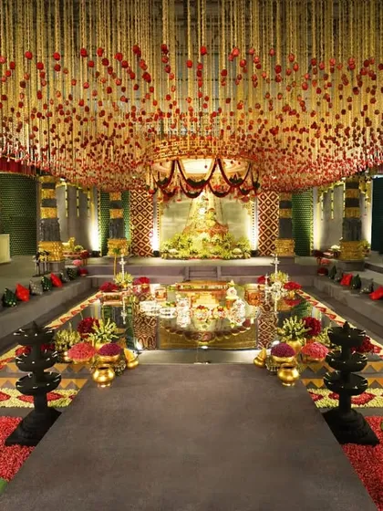 We transformed a hotel ballroom into a breathtaking temple sanctuary. This wide view showcases the grand scale of our design, featuring a central water body, towering custom-built pillars, and a ceiling adorned with thousands of floral strings, creating a truly immersive and sacred space for the wedding ceremony.
