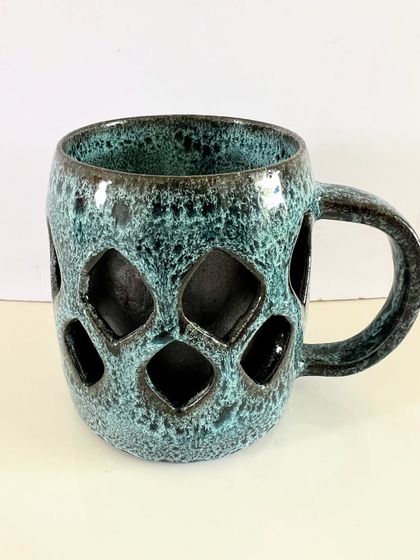 This geometric double-walled mug has a modern feel, with a repeating diamond pattern carved into the outer wall. The textured turquoise glaze adds another layer of depth and character.