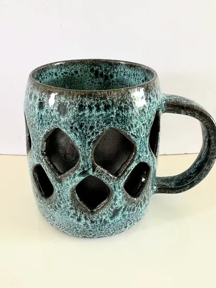 This geometric double-walled mug has a modern feel, with a repeating diamond pattern carved into the outer wall. The textured turquoise glaze adds another layer of depth and character.