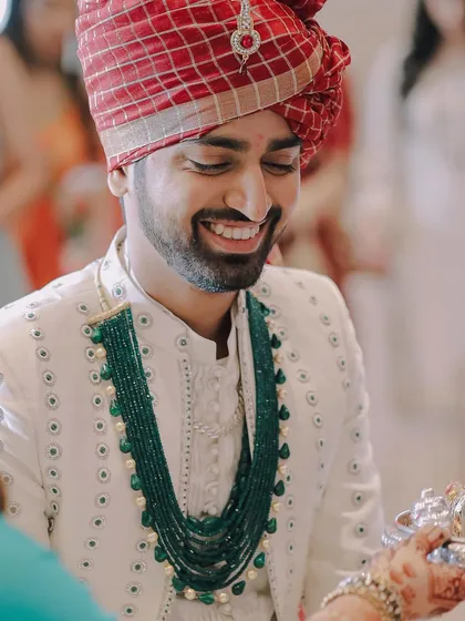 A happy, candid portrait of the groom during a wedding ritual. His genuine smile is the focus of this shot.