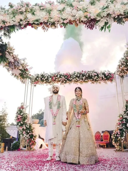 A wide shot of the couple at their floral-adorned mandap, perfectly capturing the scale of their beautiful daytime wedding ceremony.