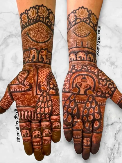 A symmetrical bridal design filled with royal animals. Both hands feature peacocks with flowing tails, while the wrists are adorned with elephant processions and lotus patterns.