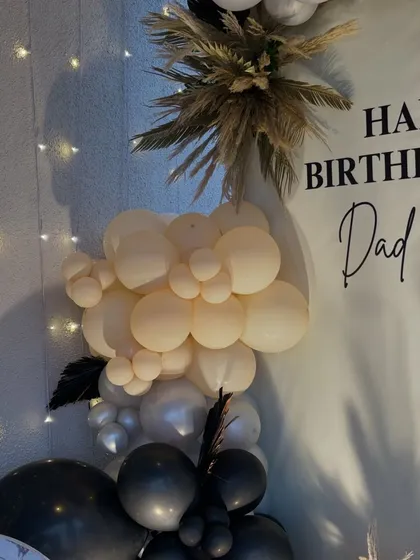 Detail of the balloon garland, showing the elegant color combination of cream, gold, and black.