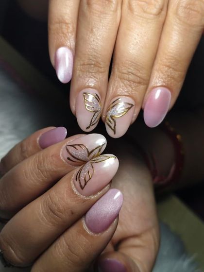 Flutter into beauty with these stunning butterfly-inspired nails. The design features delicate, gold-outlined butterflies with a touch of glitter on a soft pink cat-eye base.