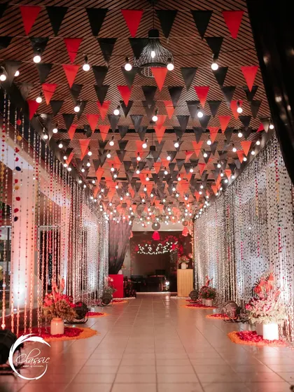 This hallway was transformed into a festive walkway with a ceiling of red and black pennant banners, string lights, and shimmering curtains, building anticipation for the party ahead.