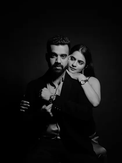 A classic and sophisticated black and white studio portrait. The dramatic lighting and their pose create a timeless and elegant image.