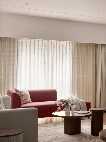 Another view of the living room in "Apartment 222," showcasing the interplay of different seating elements. The design focuses on comfort and understated elegance, with natural light enhancing the earthy tones.