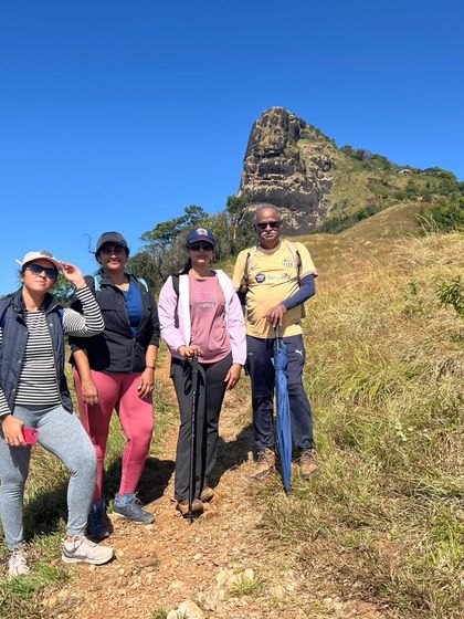 A small group with their trekking poles, with the distinctive Kurinjal peak in the background.