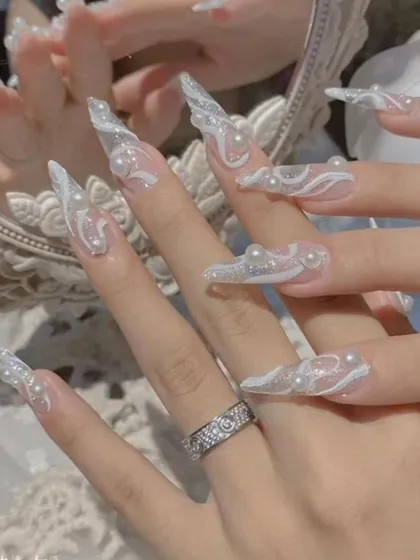 These ethereal, extra-long clear extensions are a showcase of delicate 3D art. I sculpted intricate white swirls and placed tiny pearls to create a dreamy, cloud-like effect that is both unique and elegant.