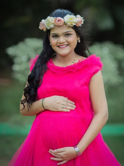 A joyful close-up portrait of a mom-to-be in a bright pink gown, her smile lighting up the photo.