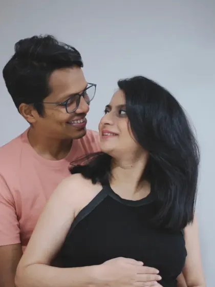 The couple shares a happy, knowing look in this candid at-home portrait, their smiles reflecting their excitement.