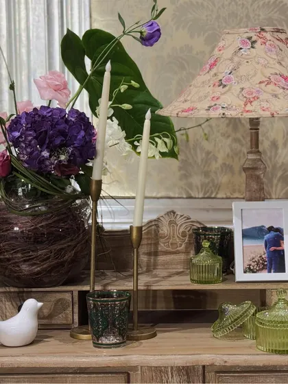 A close-up of a styled vignette with a floral lamp, taper candles, and a personal photo of the couple, adding a warm and intimate touch.