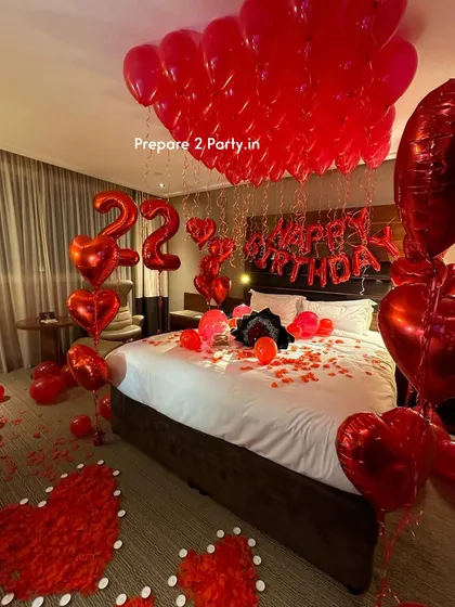 We turn standard hotel rooms into romantic retreats for birthdays and anniversaries. This classic red-themed decoration includes helium balloons on the ceiling, "Happy Birthday" foil letters, number balloons for the age, and heart shapes made of rose petals on the floor.