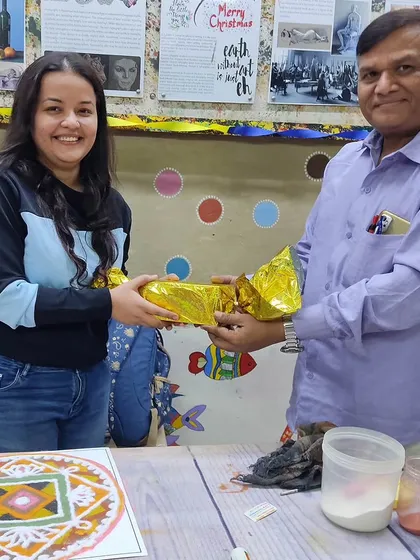 A moment from our in-person Rangoli Making Competition. Here, a participant receives a prize, celebrating the creativity and skill involved in this beautiful, traditional floor art form.
