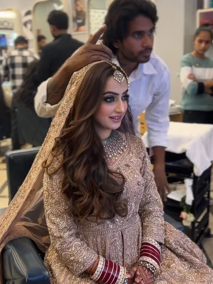 A final look at a bride with her hair styled in soft, open waves. This classic style is perfect for framing the face and complementing a heavily embroidered outfit.