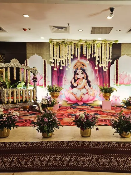 Welcome your little goddess with a beautiful Lakshmi-themed cradle ceremony. This setup includes a custom backdrop of the deity, an ornate jhoola or cradle, and floral arrangements in golden vases to create a truly blessed event.